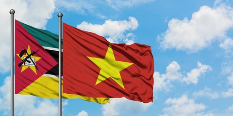Mozambique and Vietnam flag waving in the wind against white cloudy blue sky together. Diplomacy...