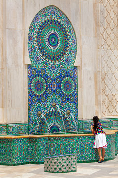 Tourist woman taking photo of fountain at mosque of Hassan II in Casablanca