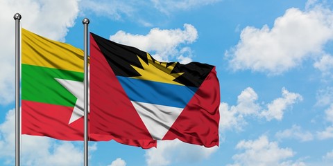 Myanmar and Antigua and Barbuda flag waving in the wind against white cloudy blue sky together....