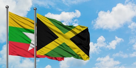 Myanmar and Jamaica flag waving in the wind against white cloudy blue sky together. Diplomacy concept, international relations.
