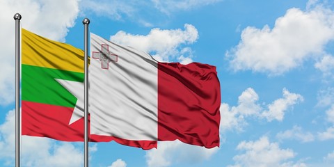 Myanmar and Malta flag waving in the wind against white cloudy blue sky together. Diplomacy...