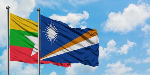 Myanmar and Marshall Islands flag waving in the wind against white cloudy blue sky together. Diplomacy concept, international relations.