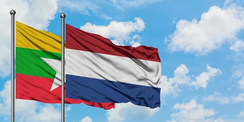 Myanmar and Netherlands flag waving in the wind against white cloudy blue sky together. Diplomacy...