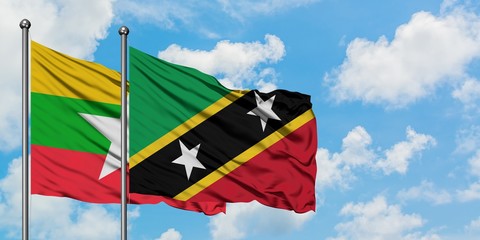 Myanmar and Saint Kitts And Nevis flag waving in the wind against white cloudy blue sky together. Diplomacy concept, international relations.