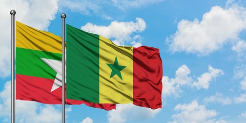 Myanmar and Senegal flag waving in the wind against white cloudy blue sky together. Diplomacy...