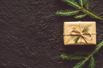 Craft gift boxe and fir branches on a black background. Top view, flat lay, copy space