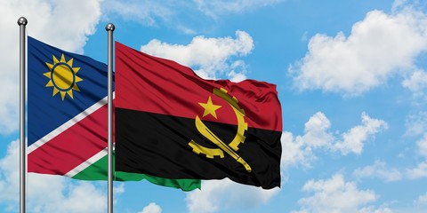 Namibia and Angola flag waving in the wind against white cloudy blue sky together. Diplomacy concept, international relations.
