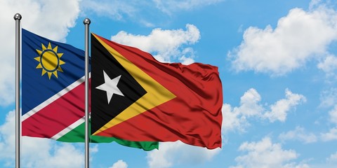 Namibia and East Timor flag waving in the wind against white cloudy blue sky together. Diplomacy concept, international relations.