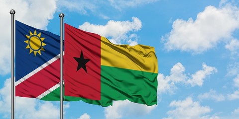 Namibia and Guinea Bissau flag waving in the wind against white cloudy blue sky together. Diplomacy concept, international relations.