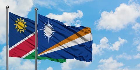 Namibia and Marshall Islands flag waving in the wind against white cloudy blue sky together. Diplomacy concept, international relations.