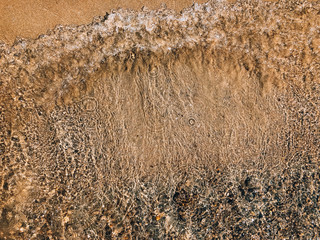 Transparent sea wave on a sandy beach. Beautiful background with wild beach with copyspace. © Simon
