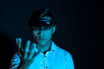 The Asian young man with virtual reality glasses. Experience mixed reality hololens headset in studio with advanced technology