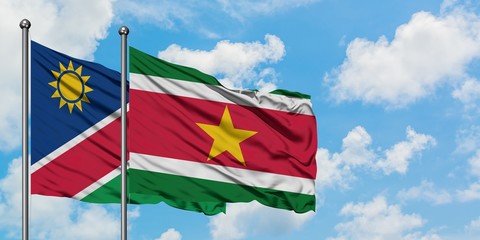 Namibia and Suriname flag waving in the wind against white cloudy blue sky together. Diplomacy concept, international relations.