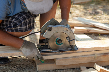 A worker cuts a wooden board at a construction site