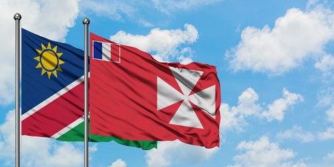 Namibia and Wallis And Futuna flag waving in the wind against white cloudy blue sky together. Diplomacy concept, international relations.