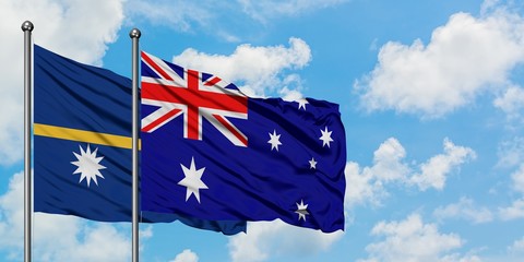 Nauru and Australia flag waving in the wind against white cloudy blue sky together. Diplomacy...