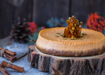 Pumpkin pie or cheesecake  with caramel  on decorative plate. Whole pie in soft focus in background. Macro with shallow dof