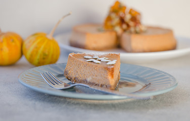 Pumpkin pie or cheesecake with caramel  on decorative plate. Whole pie in soft focus in background. Macro with shallow dof