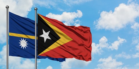 Nauru and East Timor flag waving in the wind against white cloudy blue sky together. Diplomacy concept, international relations.