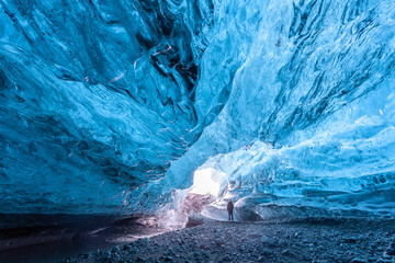 Tourist standing in an ice cave in Vatnajökull glacier Iceland - Powered by Adobe