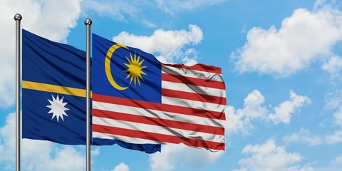 Nauru and Malaysia flag waving in the wind against white cloudy blue sky together. Diplomacy...