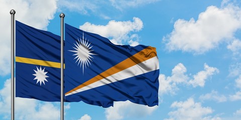 Nauru and Marshall Islands flag waving in the wind against white cloudy blue sky together. Diplomacy concept, international relations.