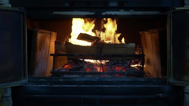 Slow burning logs In a vintage brick fireplace with screen in front of the fire. Close up and Zoom out