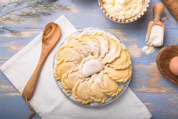 Raw dumplings, pierogi or pyrohy, varenyky, vareniki, served with cottage cheese on board. National Russian cuisine, natural organic homemade bakery product, view from above.