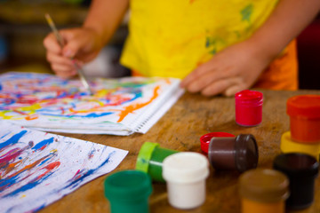 Naklejka premium Child hand with brushes drawing. Child drawing top view.