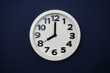 White round clock showing eight o'clock on blue background