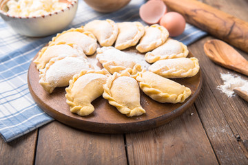 Raw dumplings, pierogi or pyrohy, varenyky, vareniki, served with cottage cheese on board. National Russian cuisine, natural organic homemade bakery product, view from above.