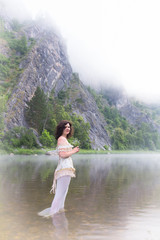 Beautiful young woman on the river in the morning fog