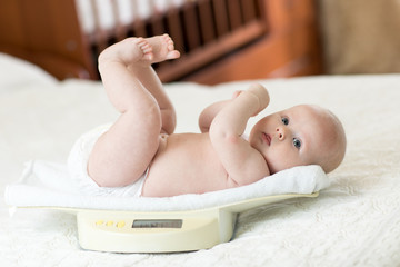 Cute little baby newborn lying on scales at home