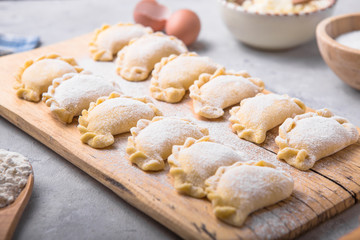Raw dumplings, pierogi or pyrohy, varenyky, vareniki, served with cottage cheese on board. National Russian cuisine, natural organic homemade bakery product, view from above.