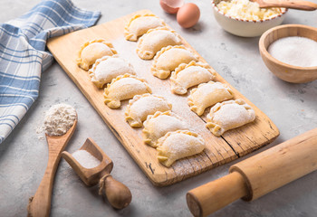 Raw dumplings, pierogi or pyrohy, varenyky, vareniki, served with cottage cheese on board. National Russian cuisine, natural organic homemade bakery product, view from above.