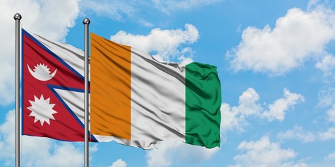 Nepal and Cote D'Ivoire flag waving in the wind against white cloudy blue sky together. Diplomacy...