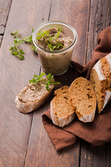 Fresh homemade chicken liver pate on bread and in jar on a dark wooden background