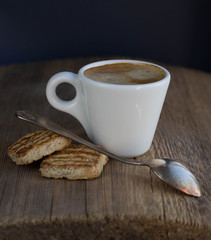 White small cup of espresso with cookies and spoon on old wooden table dark mood photo