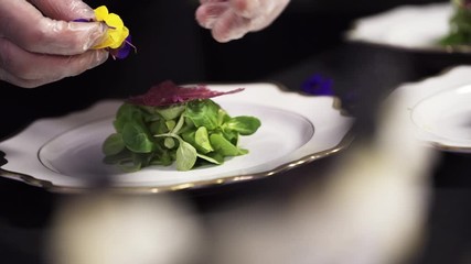 Catering company preparing large numbers of food beautifully decorating it, delicious gourmet meal is being given the finishing touches by the chef in a restaurant.