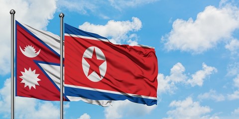 Nepal and North Korea flag waving in the wind against white cloudy blue sky together. Diplomacy concept, international relations.
