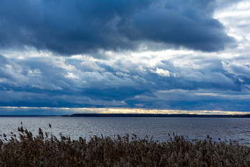 Low and dark clouds above the river before the rain. Dramatic landscape.