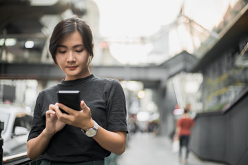 Fototapeta na wymiar Happy asian woman looking at her phone in the city