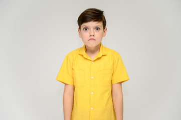 Concept boy teenager shows imitates the behavior of heroes from different movies. Portrait of a child on a white background in a yellow shirt. Standing in front of the camera in poses with emotions.