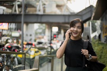 Happy asian woman talking with smartphone in the city