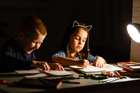 Little girl and boy doing homework in evening at home