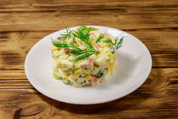 Salad with crab sticks, sweet corn, cucumber, eggs and mayonnaise on wooden table