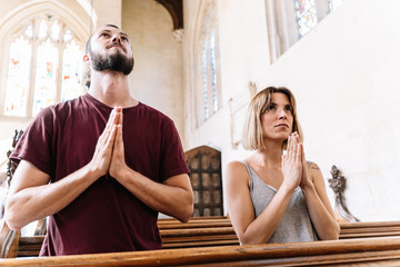 Young couple praying in a church looking up at the sky