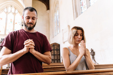 Stock photo of a young couple praying in a church