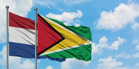 Netherlands and Guyana flag waving in the wind against white cloudy blue sky together. Diplomacy concept, international relations.