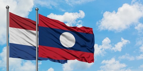 Netherlands and Laos flag waving in the wind against white cloudy blue sky together. Diplomacy concept, international relations.